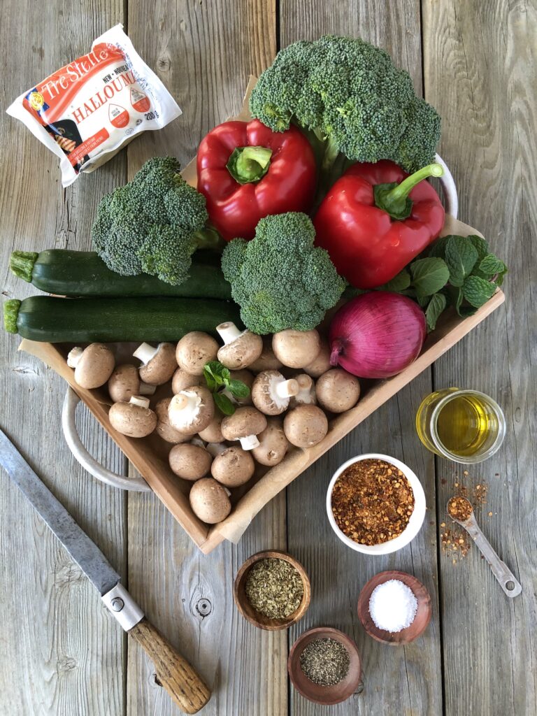 Tray of fresh veggies including broccoli, zucchini, and mushrooms