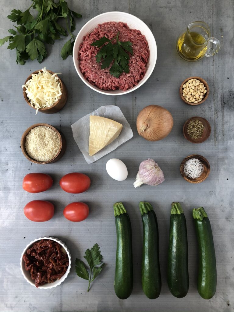 Zucchini, ground beef, olive oil, tomatoes, and other ingredients artfully arranged