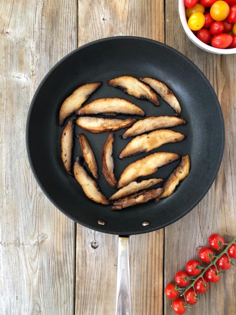 Mushrooms browned and cooked in a skillet.