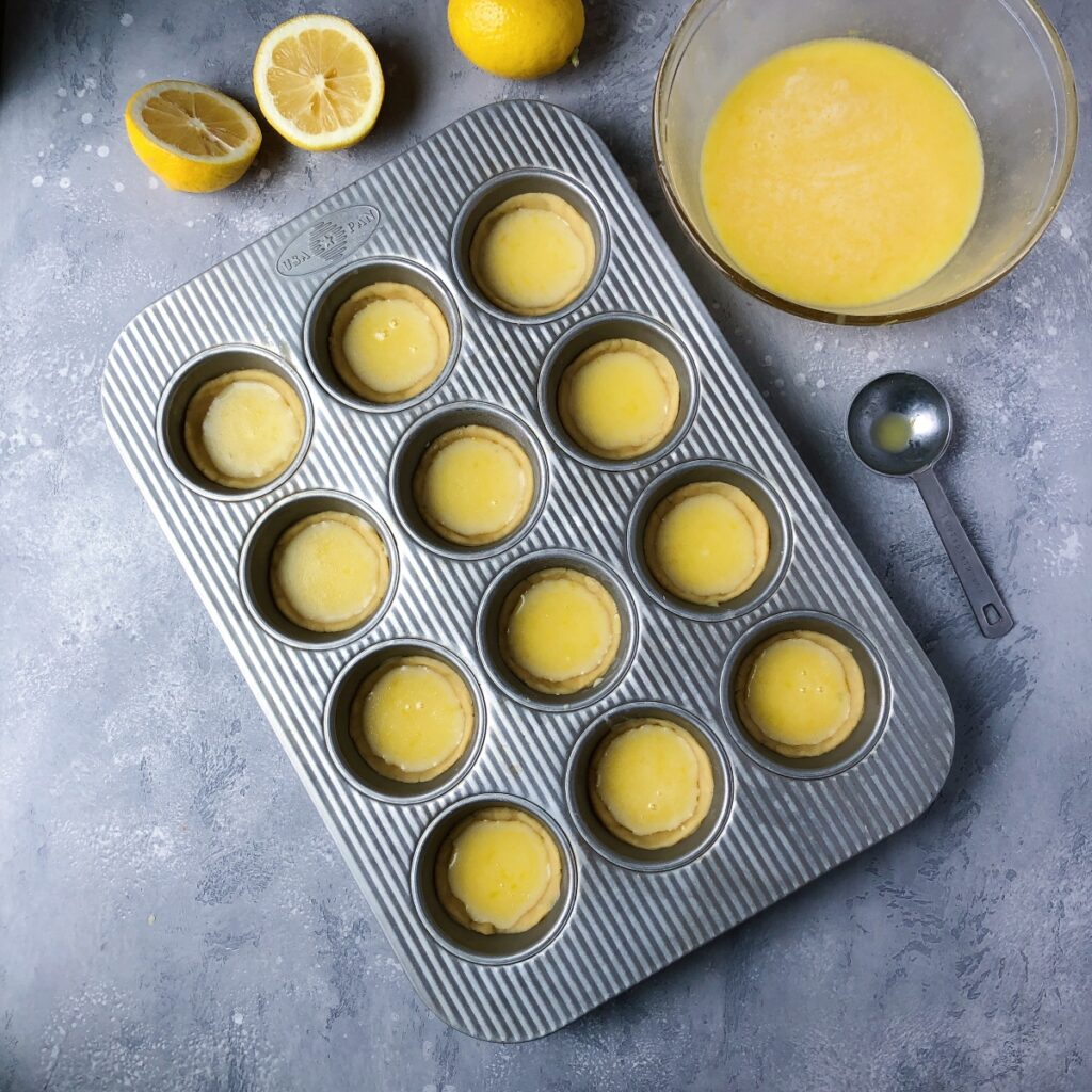 Lemon curd poured into formed tart shells.