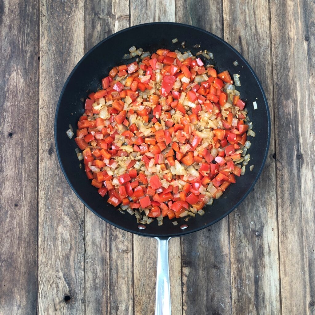 Onions and peppers sautéed in a skillet.
