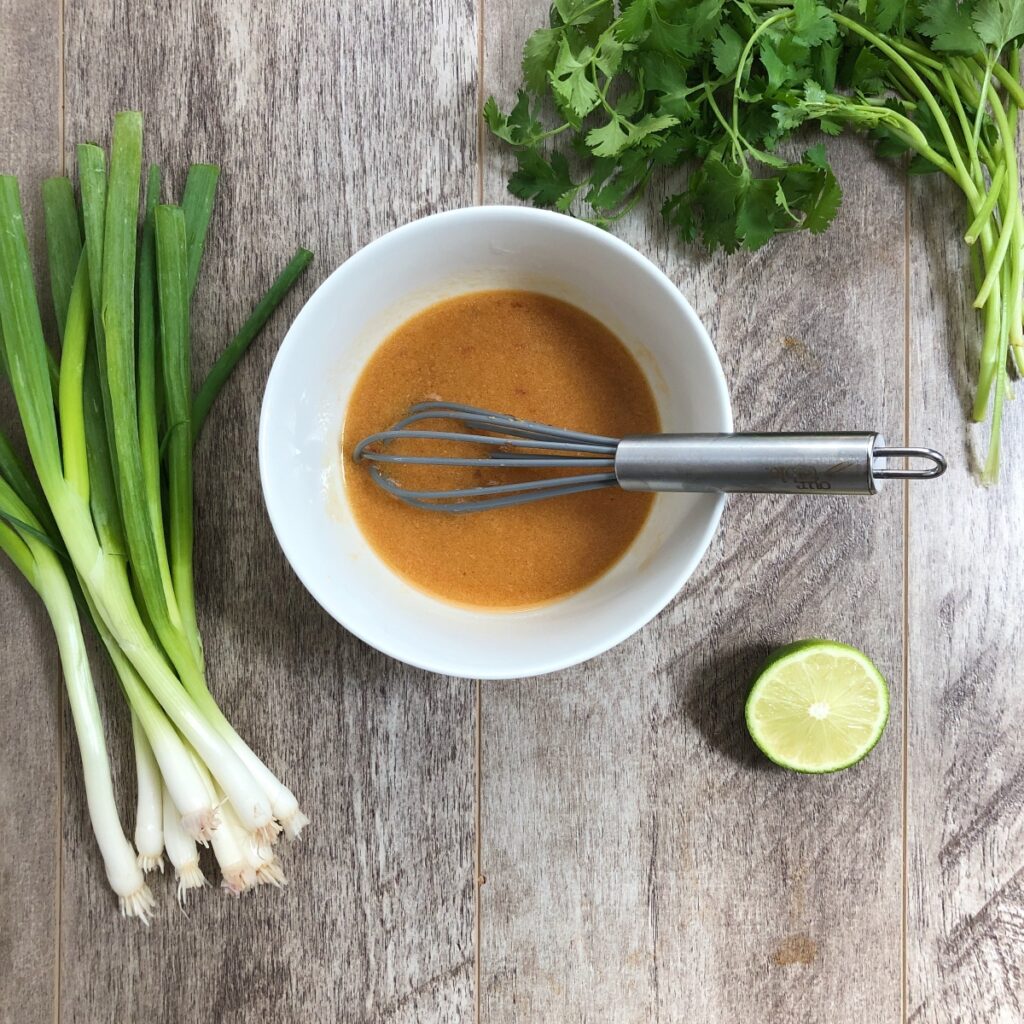 Sesame miso dressing whisked in a white bowl.