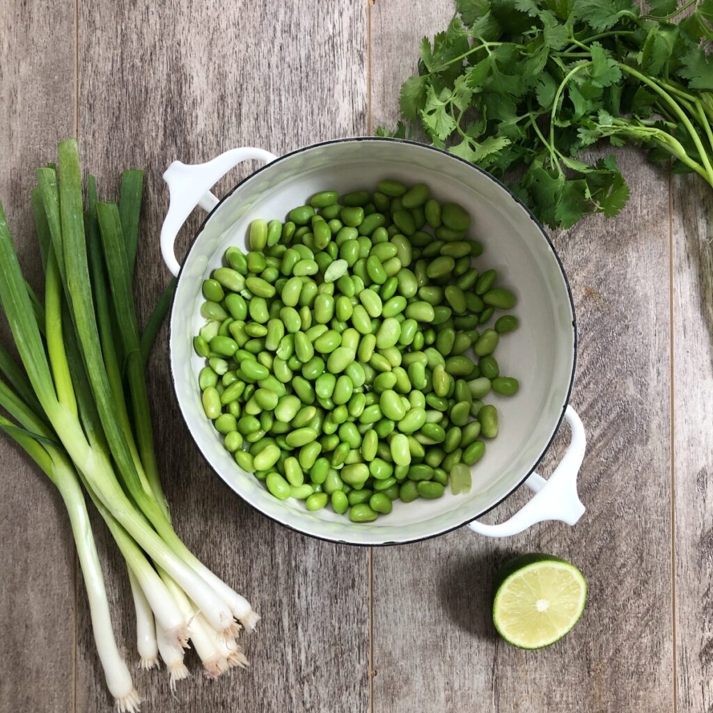 Edamame beans blanched and drained in a white saucepan.