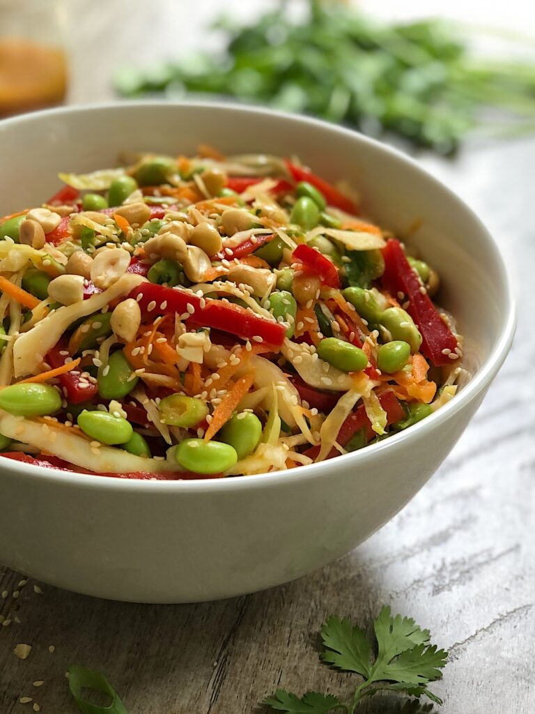 Close view of salad in a white serving bowl tossed in miso sesame ginger dressing.